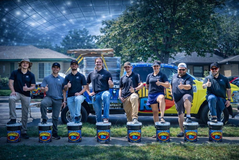 Team of professionals in matching shirts thumbs up with a colorful truck and roofing materials.